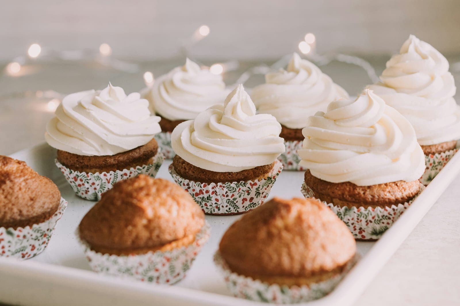 Cupcakes topped with swirls of white frosting on a white tray.