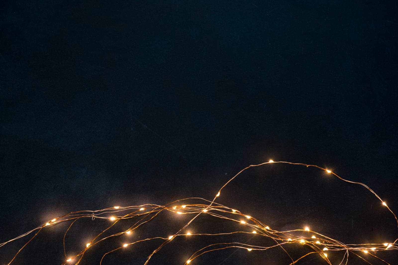 A tangle of warm fairy lights glowing against a dark midnight-blue background.